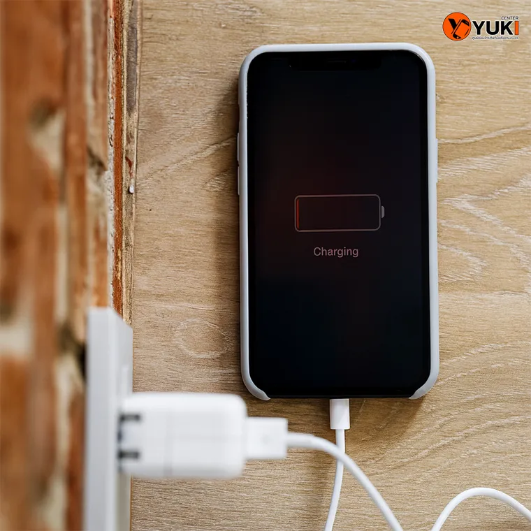 ภาพมือถือ iPhone เสียบสายชาร์จกับปลั๊กไฟ แบตเตอรี่ขึ้นต่ำใกล้หมด แสดงปัญหาชาร์จไม่เข้า