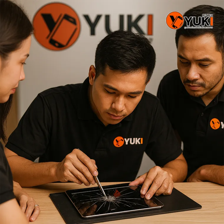 ทีมช่าง Yuki Center กำลังซ่อม iPad หน้าจอแตกด้วยความละเอียดและใส่ใจ พร้อมสวมเสื้อโลโก้ร้านเพื่อแสดงความเป็นมืออาชีพ