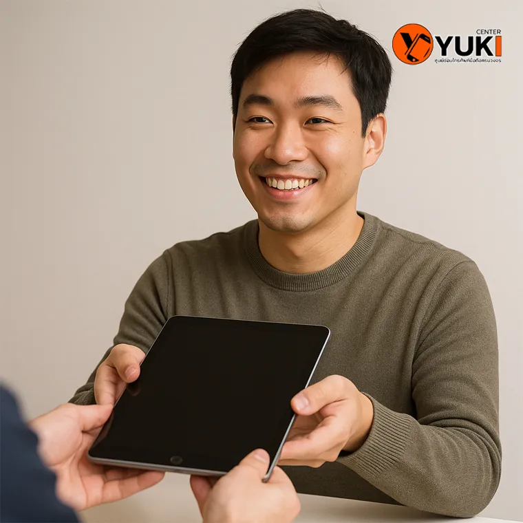 ภาพช่างกำลังส่งมอบ iPad หลังเปลี่ยนแบตเตอรี่เสร็จ พร้อมรอยยิ้มของลูกค้าที่พอใจ บริการจากร้านซ่อม iPad มืออาชีพ Yuki Center