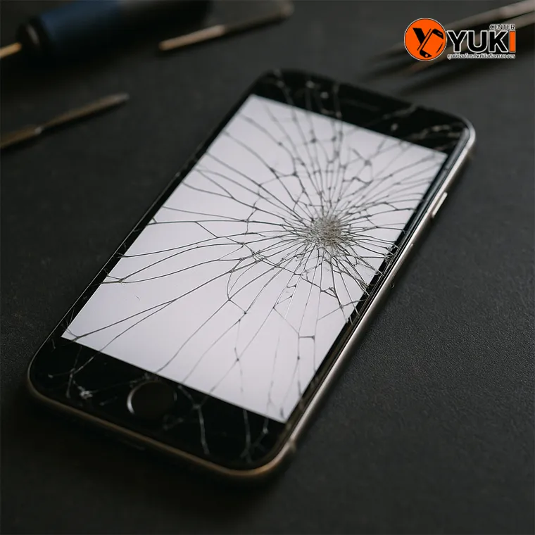 ภาพหน้าจอ iPhone แตกอย่างรุนแรง วางบนโต๊ะซ่อมที่ร้าน Yuki Center