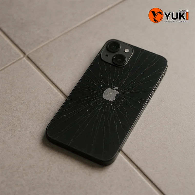 “ภาพ iPhone 16 ฝาหลังแตกกระจายหลังจากตกพื้น มุมมองบนพื้นกระเบื้อง โดยศูนย์ซ่อม Yuki Center”
