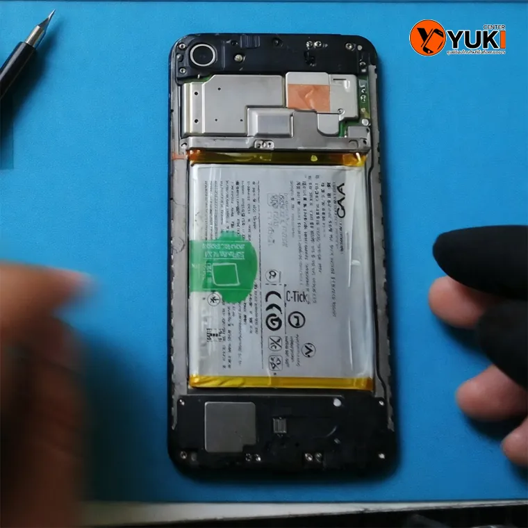 ช่างกำลังเปลี่ยนแบตเตอรี่ Vivo ภายในเครื่องบนโต๊ะซ่อมมาตรฐาน