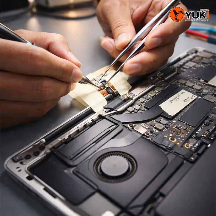 ช่างกำลังซ่อม MacBook ภายในเครื่อง อย่างละเอียด บนโต๊ะซ่อมมาตรฐาน ใกล้ฟิวเจอร์รังสิต