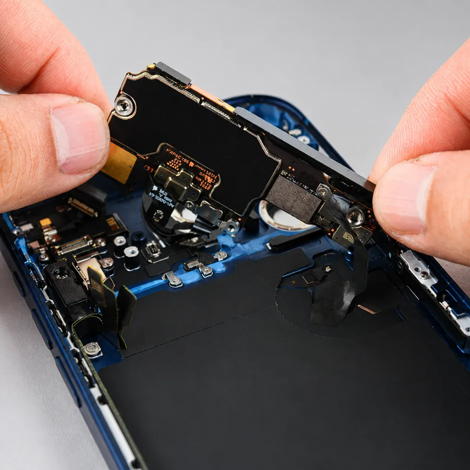 ช่างซ่อมเมนบอร์ด iPhone กำลังถอดและตรวจเช็กแผงวงจรภายในเครื่องที่ Yuki Center